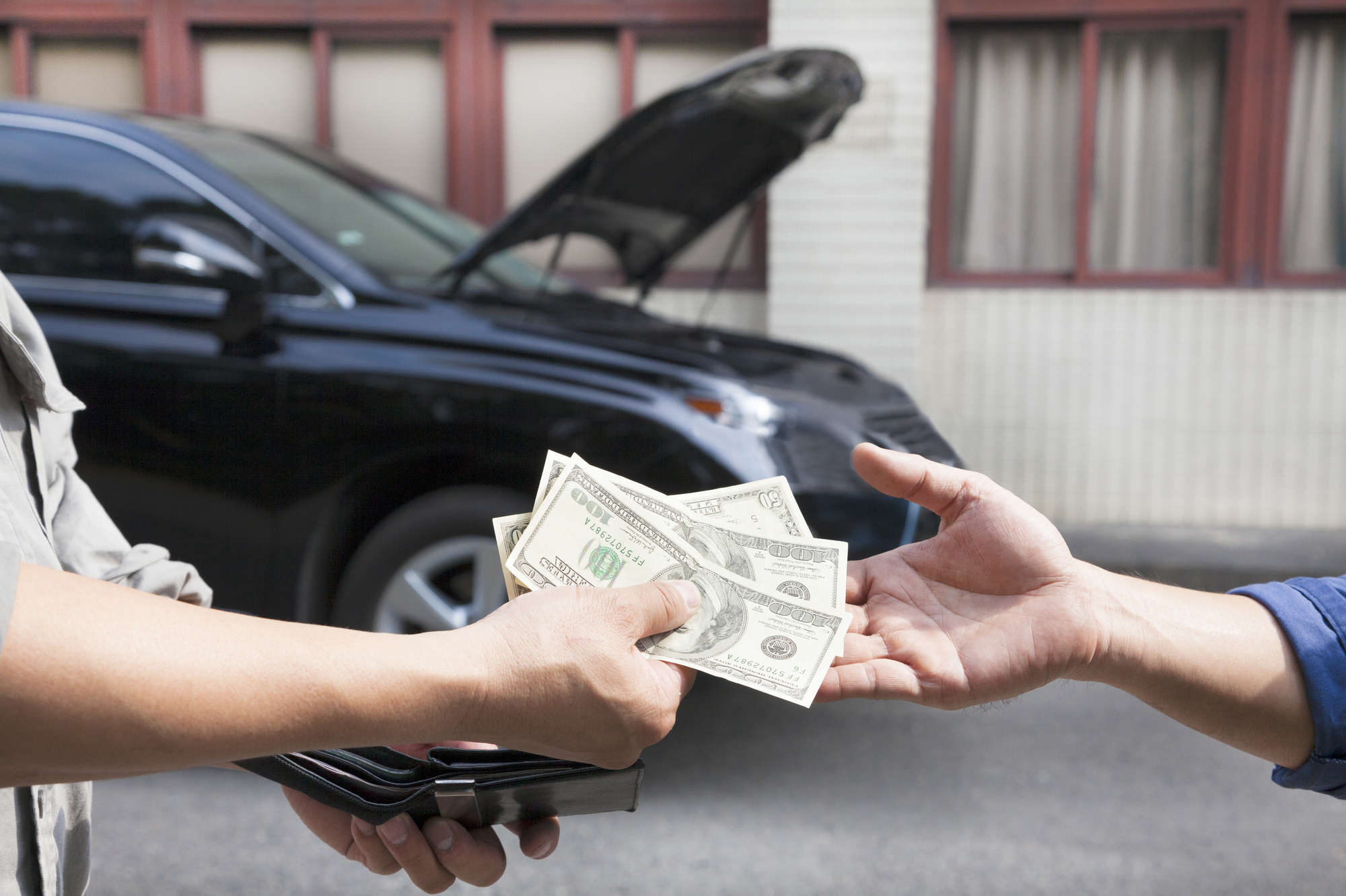 hands exchanging money for car repairs