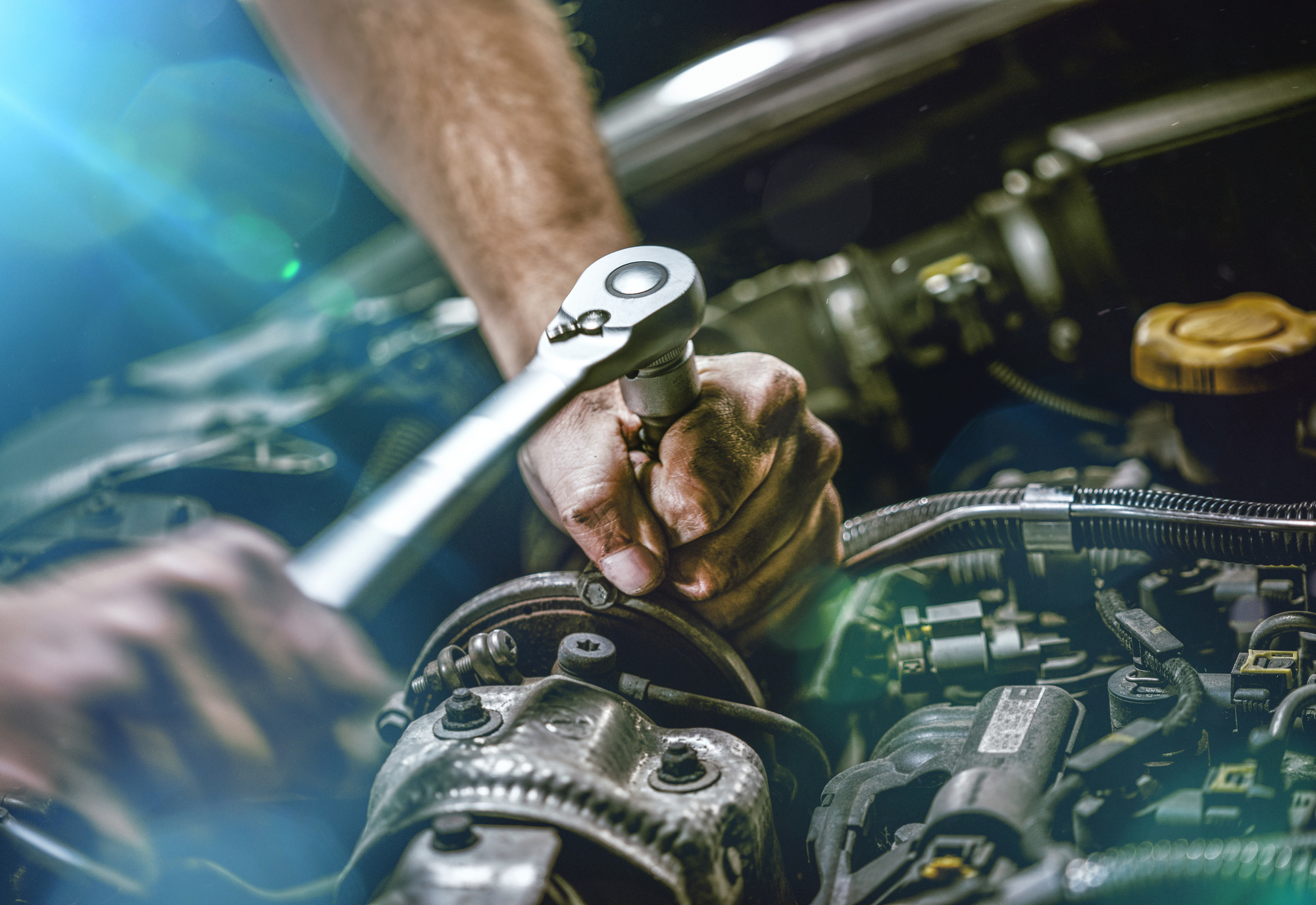 man fixing car with socket wrench