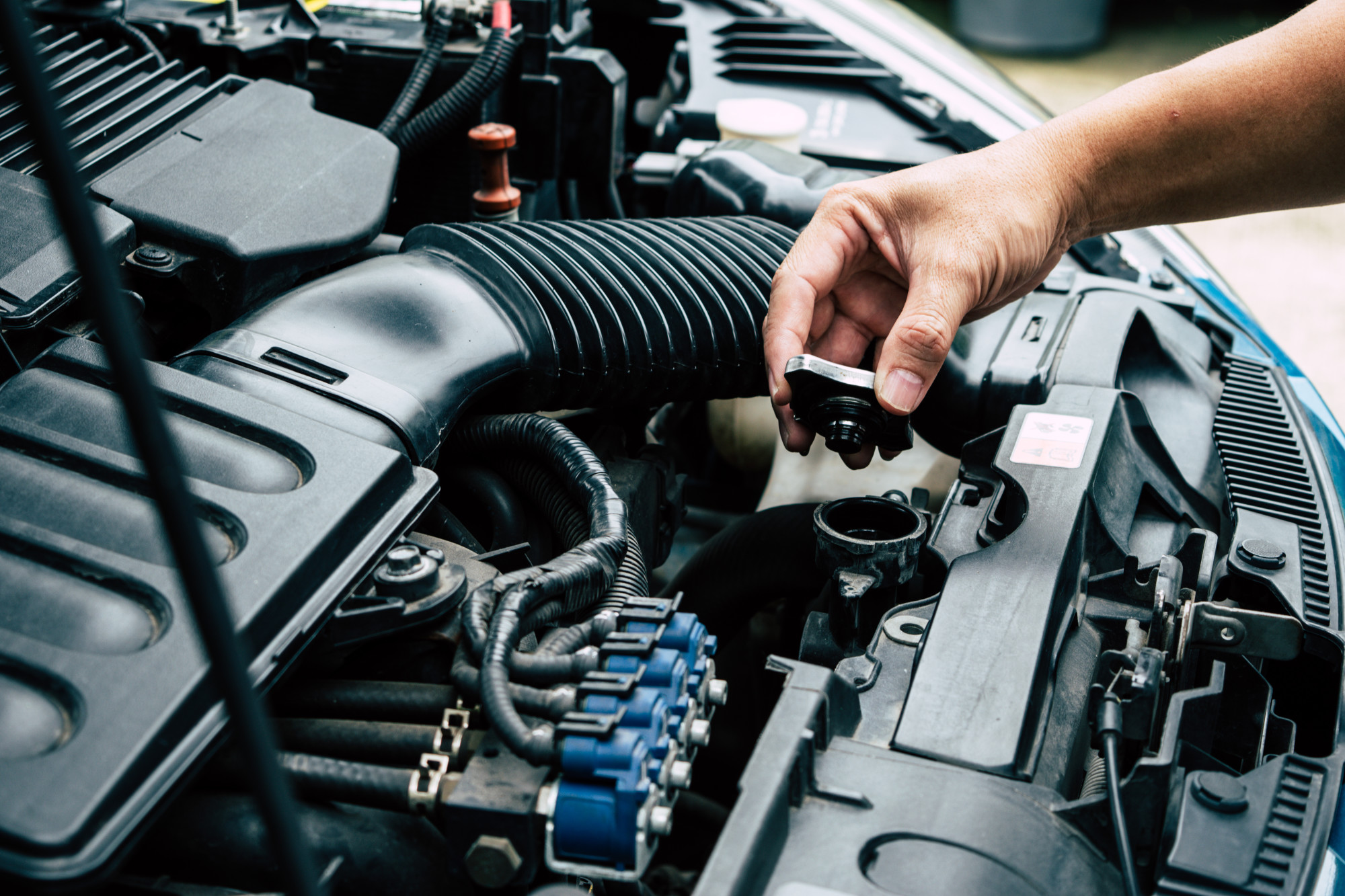 car engine with hand holding cap