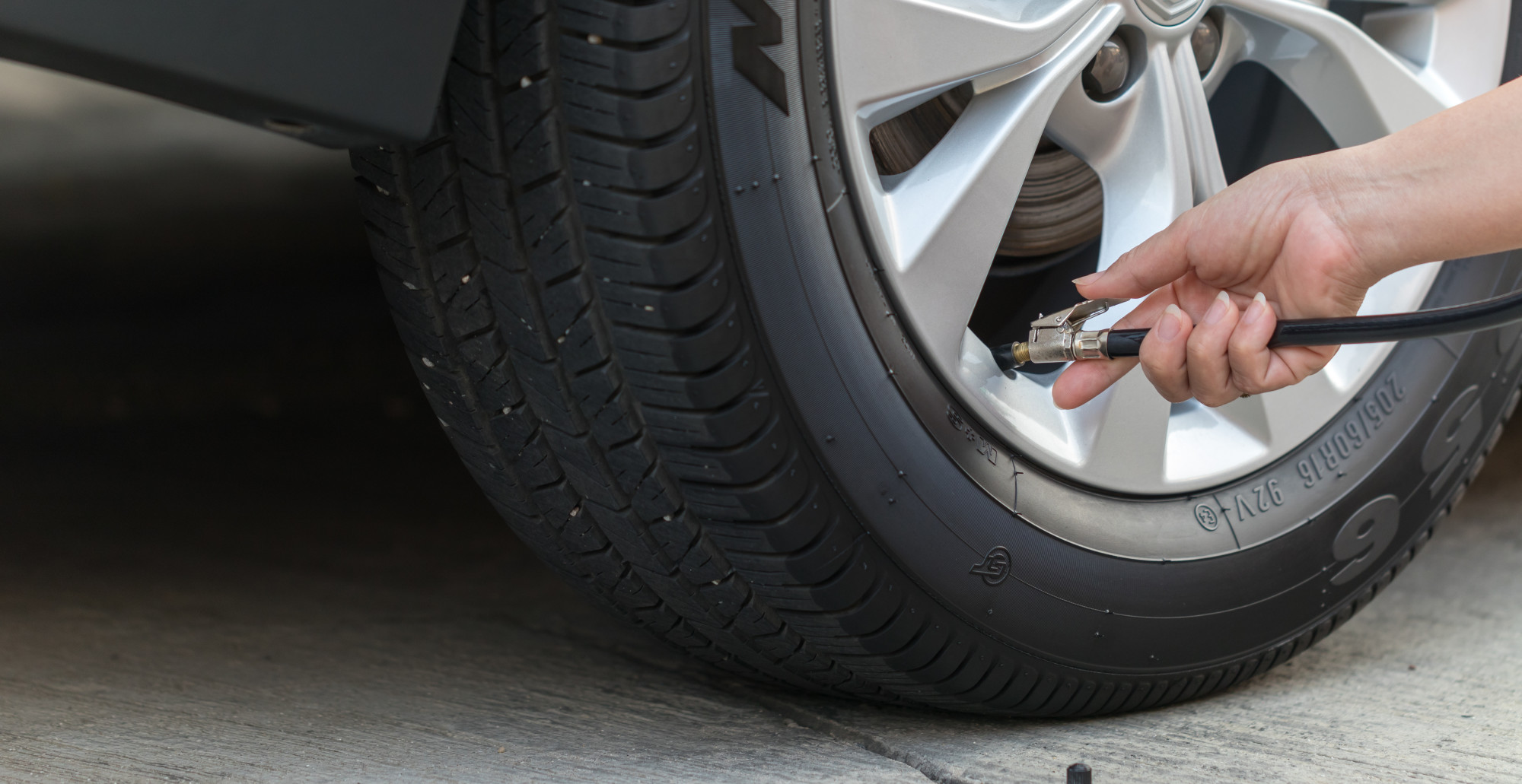 person filling car tire with air