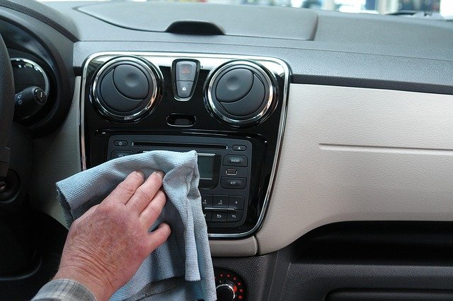 Person Cleaning the Dashboard of a Car Using a Microfiber Cloth